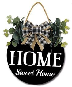 a black and white sign that says home sweet home with a bow hanging from it