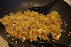 rice and carrots are being cooked in a skillet