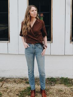 a woman standing in front of a white building with her hands on her hips and looking off to the side