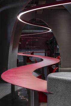 a curved table in a room with red chairs