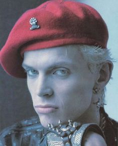 a woman wearing a red beret with spikes on it's ear and piercings