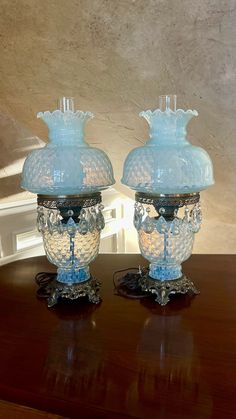 two blue glass vases sitting on top of a wooden table