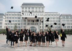 a group of people in graduation gowns throwing their caps in the air at an university