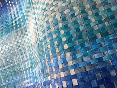 a blue and white mosaic tile wall next to a window with the sun shining through it