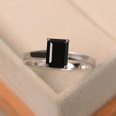 a black diamond ring sitting on top of a white cushioned surface in a box