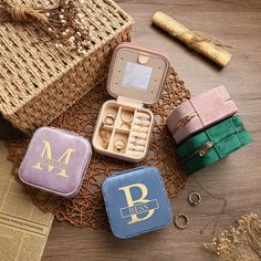 four small jewelry cases sitting on top of a wooden table next to a straw basket