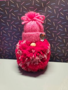 a small pink stuffed animal with a hat on it's head sitting on a table