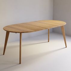 an oval wooden table with two legs in the middle, against a plain white wall