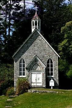 an old stone church with a steeple surrounded by trees