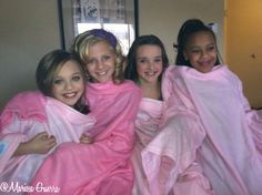 four girls wrapped in pink towels posing for the camera