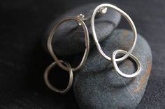 - Higher Karen silver content of 95-99%  - Made of 2 handmade oval loops, interlocking one to another - Length: 48mm; Size of loops: bigger ring 32 mm, smaller 19 mm; Weight 7.26g - Local Karen packaging to support women in the community - We have a similar style necklace and bracelet in our shop These earrings are made of 2 handmade oval loops, interlocking one to another. Loops are slightly irregular, following an organic oval shape. They were created from a square-profile 2 mm silver wire, in 95-99%silver,  that was etched on the surface to give it a more handmade, artisan-crafted feel. The posts and stoppers are in sterling silver. We have a similar style necklace and bracelet in our shop. All our silver products are created in 95-99% Silver which is typical of the Thai Karen hill-trib Loops Earrings, Round Garnet Ring, Lemon Quartz Ring, Rhodolite Garnet Ring, Swiss Blue Topaz Ring, Support Women, Cushion Cut Ring, Loop Earrings, Big Rings