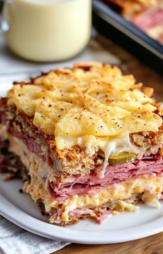 a close up of a plate of food with meat and cheese on it next to a glass of milk