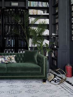 a green velvet couch in front of a bookshelf