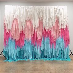 an art installation made out of paper strips and colored yarns on a white wall