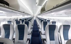 the inside of an airplane with rows of empty seats and blue carpeted flooring