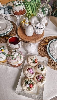 a table topped with plates filled with cakes and cupcakes next to baskets full of flowers