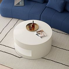 a white coffee table sitting on top of a rug next to a blue sectional couch