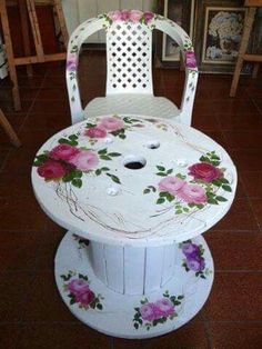 a white chair with flowers painted on it's seat and wheels, sitting in a room