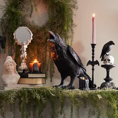 a black crow statue sitting on top of a table next to candles and other decorations