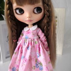 a doll with long brown hair wearing a pink dress