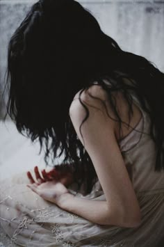 a woman sitting on top of a bed covered in white sheets