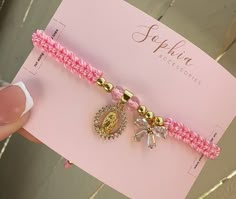 a pink bracelet with two charms on it and a card in the background that says, sophiin accessories