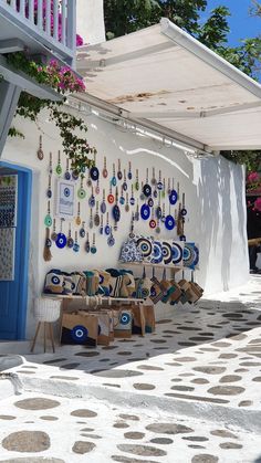 an outdoor shop with lots of earrings hanging on the wall and tables in front of it