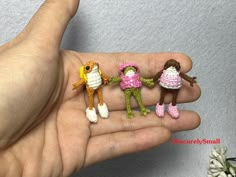 three tiny crocheted dolls are held in the palm of a person's hand