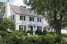 a white house surrounded by trees and bushes