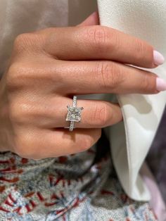 a woman's hand with a diamond ring on her finger and a white shirt