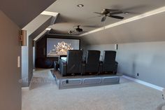 an empty home theater room with chairs and a projector screen in the middle of the room