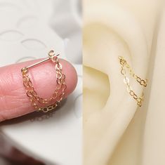 a person's left hand with a pair of gold chain earrings on top of them