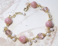 Beautiful Peruvian pink opals are accented with blush hued Swarovski crystals. Small white freshwater pearls dangle and make this bracelet unique and fun. A stunning gift for a woman born in October since the opal is her birthstone. A subtle natural pink gemstone jewelry, artisan and elegant, perfect for weddings and dressy occasions.Bracelet Details:- Pink opal gemstones are 9 mm. Pearls are 3 - 4 mm.- Bracelet length is 7.5 inches long (19.05 cm) plus a 1 inch extender- Handmade with 14k gold Pink And Pearl Bracelet, Elegant Beaded Rose Quartz Jewelry, Elegant Pink Opal Jewelry With Natural Stones, Elegant Rose Quartz Beaded Jewelry, Elegant Pink Round Beaded Bracelets, Pink Rose Quartz Jewelry With Stones, Delicate Pink Round Bracelets, Delicate Pink Round Bead Jewelry, Handmade Elegant Pink Opal Jewelry