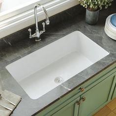 a white sink sitting on top of a kitchen counter next to a potted plant