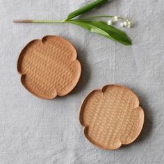 two wooden trays sitting on top of a white table cloth next to a green plant