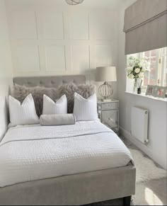 a bed with white sheets and pillows in a bedroom