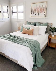 a bed with white sheets and green blankets in a bedroom next to two nightstands