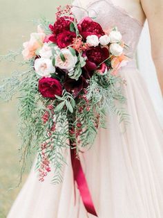 a bride holding a bouquet of red and white flowers