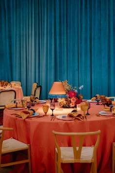 the table is set up with orange linens and place settings for two people to sit at