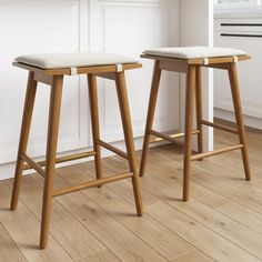 two wooden stools sitting on top of a hard wood floor next to each other