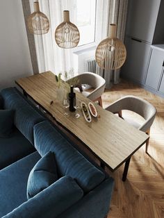 a living room with blue couches and wooden table in the center, surrounded by hanging lights