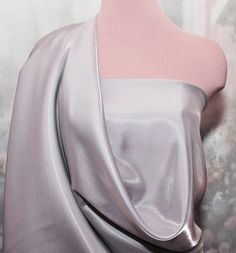 a mannequin wearing a silver dress with an asymmetrical neckline