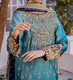 This exquisite blue wedding dress with embroidered and gold-copper work is a traditional work of art. This exquisite Kameez Trouser is the pinnacle of elegance and grace thanks to its flawless stitching and embroidered borders. The stunning kameez features hand-crafted zardosi and gold-copper accents, and it has an enticing shade of blue. This kameez is ideal for a wedding because of the embroidery on the front and around the borders. This elaborately embroidered kameez is worn as a magnificent wedding dress when coupled with tissue-fabric trousers. The pants' edges are embellished with goldwork and Gold Lehenga With Intricate Embroidery For Traditional Ceremonies, Blue Traditional Wear With Intricate Embroidery In Jamawar, Bollywood Style Dupatta With Gold Embroidery For Traditional Ceremonies, Blue Jamawar Salwar Kameez For Wedding, Gold Dupatta With Dabka For Traditional Ceremonies, Gold Embroidered Sharara For Traditional Ceremonies, Blue Salwar Kameez With Intricate Embroidery In Jamawar, Blue Salwar Kameez With Intricate Embroidery For Eid, Blue Jamawar Sharara For Wedding