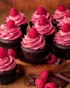 chocolate cupcakes with raspberry frosting on a wooden plate