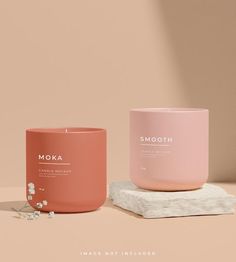 two candles sitting next to each other on top of a white marble slab with the word moka printed on it