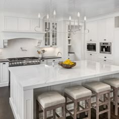 a large kitchen with white cabinets and counter tops, along with an island in the middle