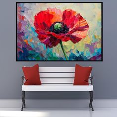 a painting on the wall above a bench with two red pillows and one orange flower