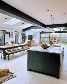 a large open kitchen and dining area with an island in the middle, surrounded by windows