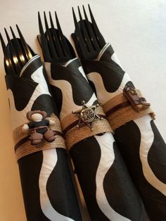 four forks are wrapped in black and white paper with brown ribbon around them, decorated like zebras