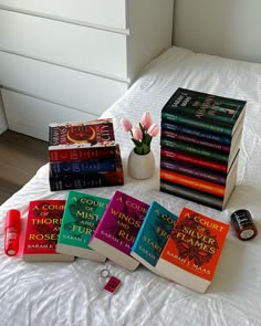 a bed topped with lots of books next to a vase filled with flowers